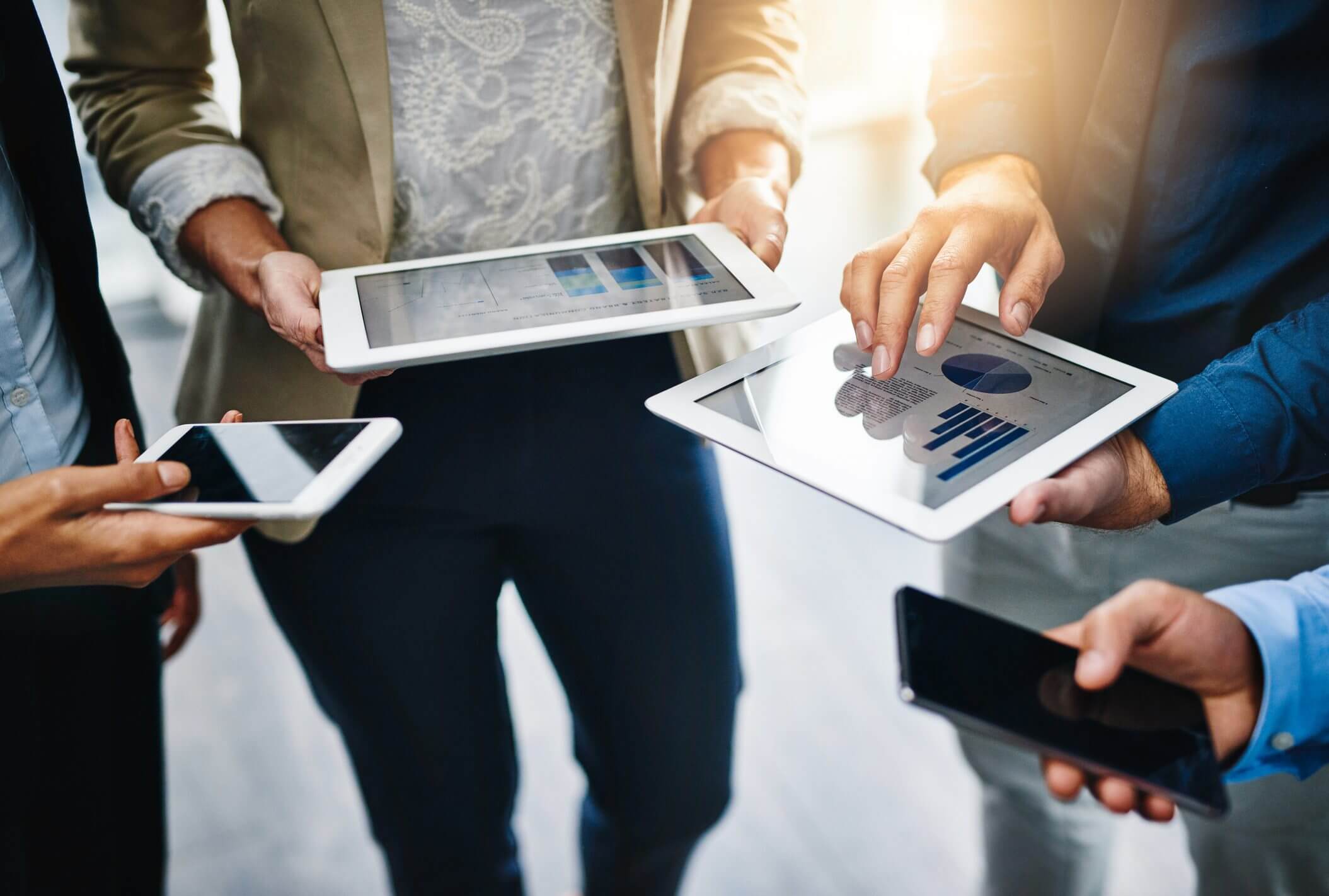People interacting with tablets and smartphones in a business setting.